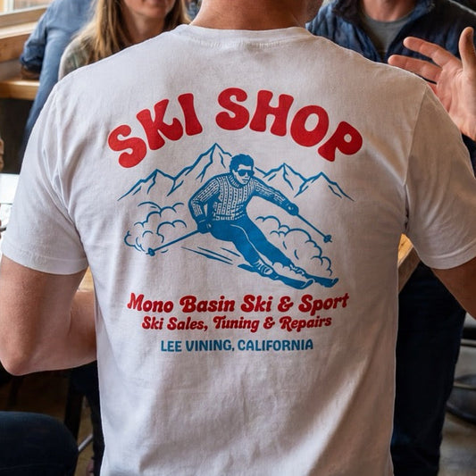 Person wearing a 'Ski Shop' t-shirt in a social setting with others.