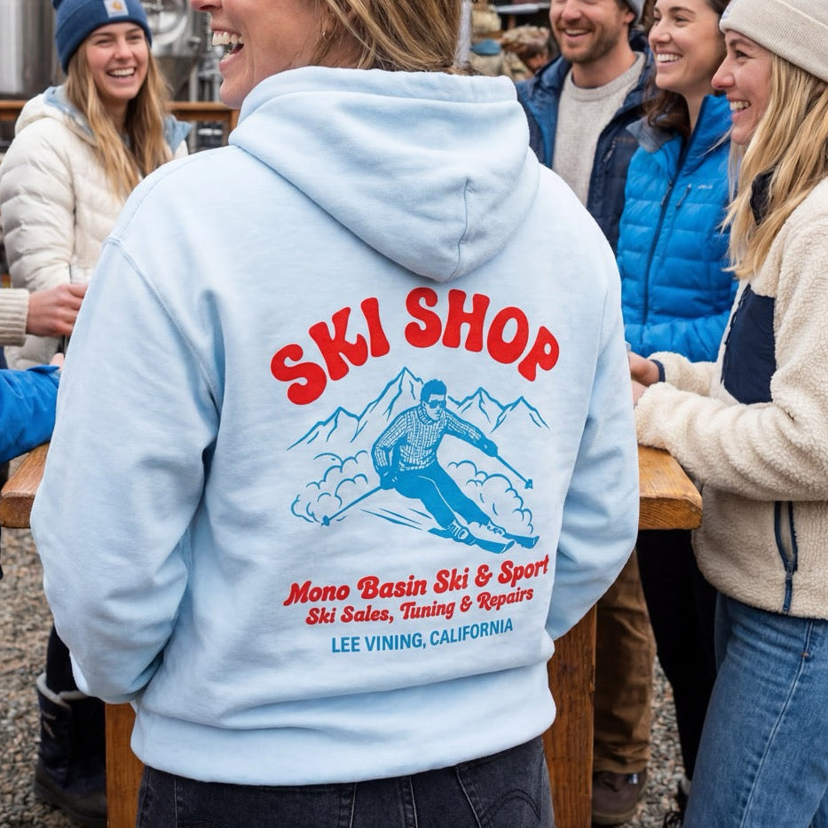 Person wearing a hoodie with 'Ski Shop' design in a snowy outdoor setting